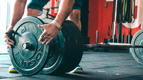 A Man Adding Free Weights to a Bar